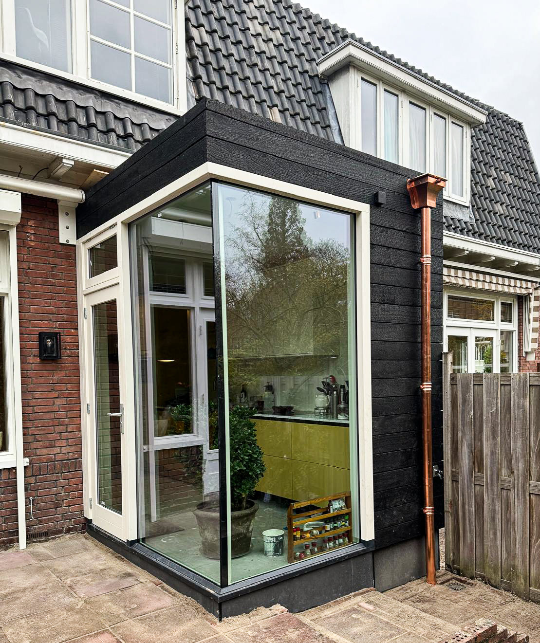 House extension in Dordrecht clad in KAEN Carbon charred Accoya with large glazing and copper downpipe
