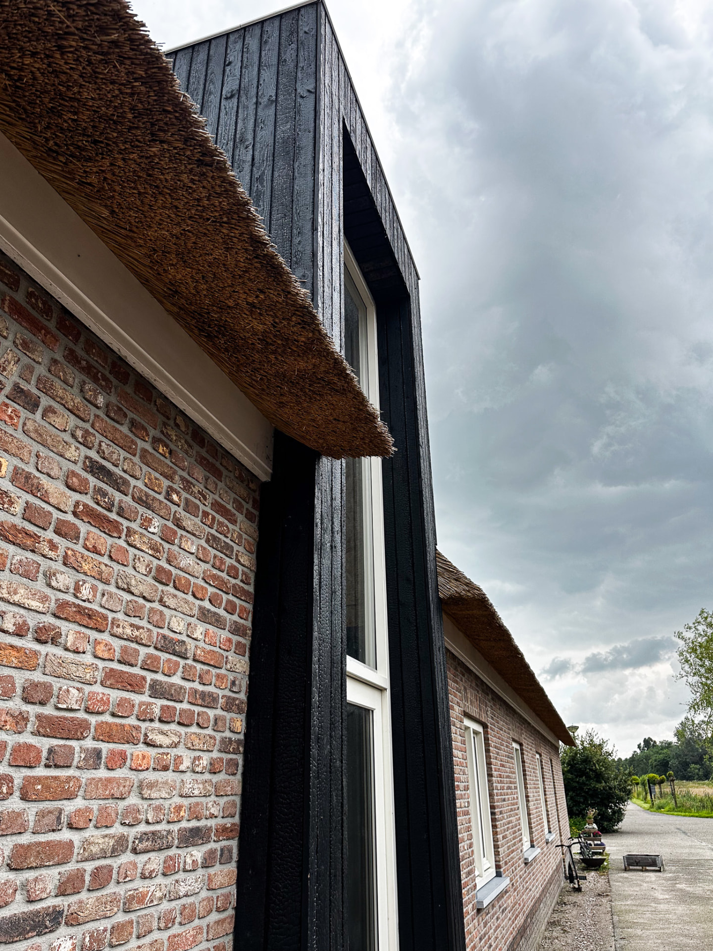 KAEN Carbon charred larch cladding beside brick and thatch on a farmhouse in Utrecht