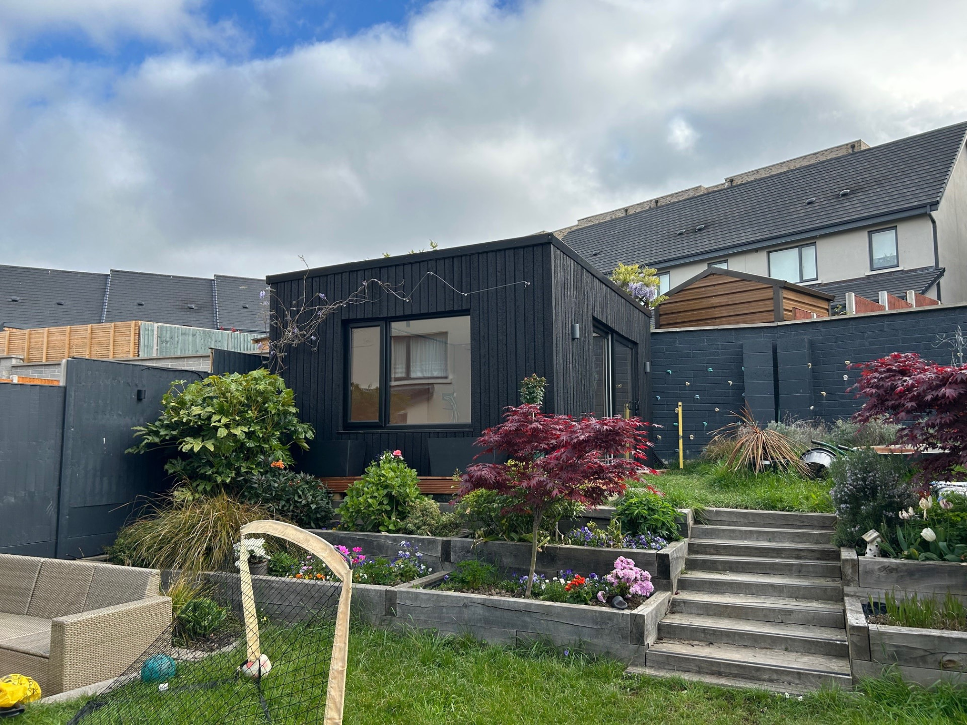 Garden room extension in Ireland clad in black charred larch above a terraced garden
