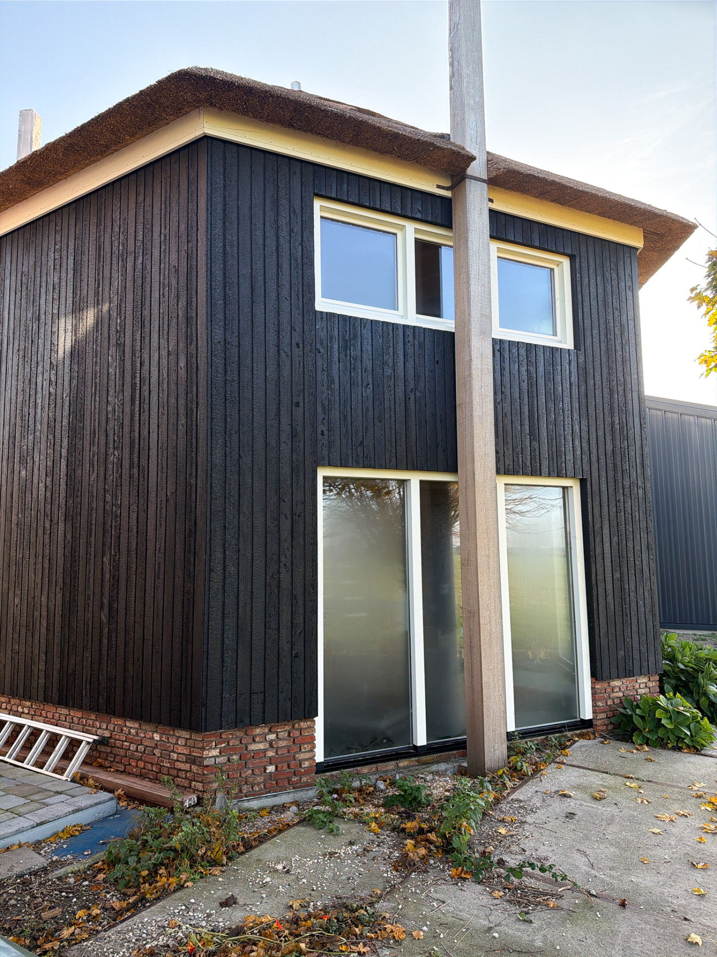 Thatched farmhouse gable clad in vertical KAEN Carbon charred larch above a brick plinth