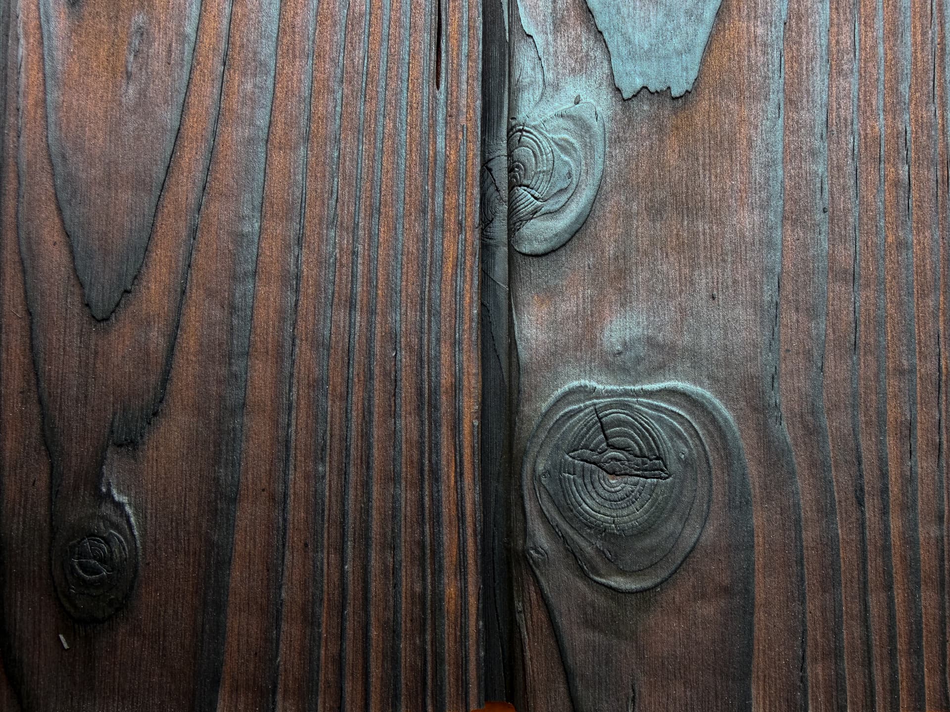 Close-up of KIME Amber charred and brushed larch with rich amber-brown tones and dark knots